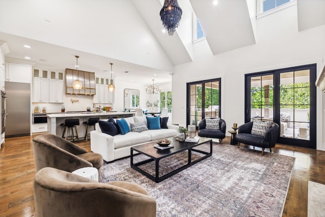 living room featuring a chandelier, french doors, hardwood / wood-style flooring, and high vaulted ceiling