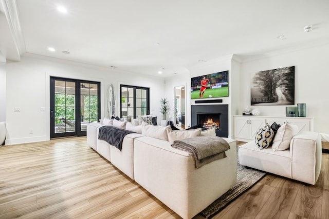 living room featuring french doors, ornamental molding, and light wood-type flooring