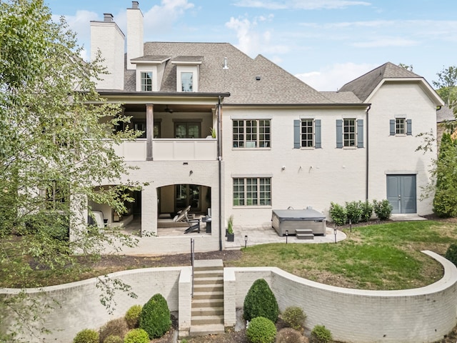 back of house with ceiling fan, a patio area, a balcony, and a hot tub