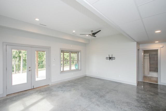 spare room featuring concrete flooring, ceiling fan, and a healthy amount of sunlight