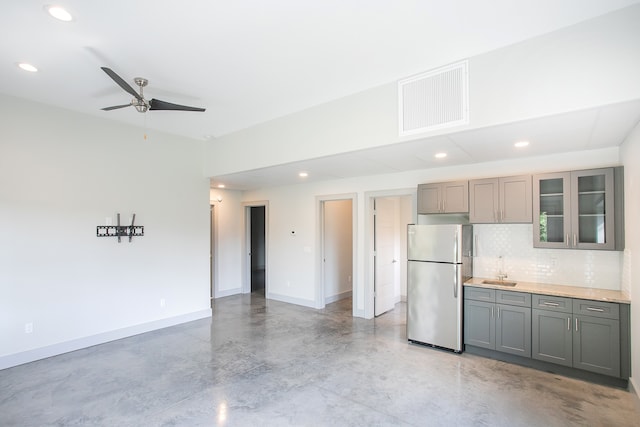 kitchen featuring gray cabinetry, tasteful backsplash, stainless steel refrigerator, ceiling fan, and sink