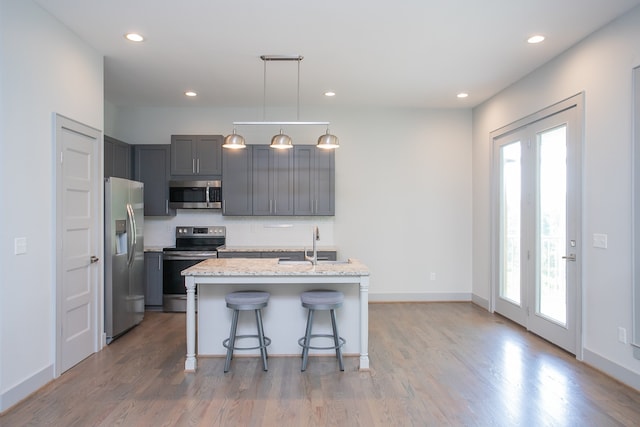 kitchen featuring a center island with sink, light stone countertops, stainless steel appliances, and a wealth of natural light