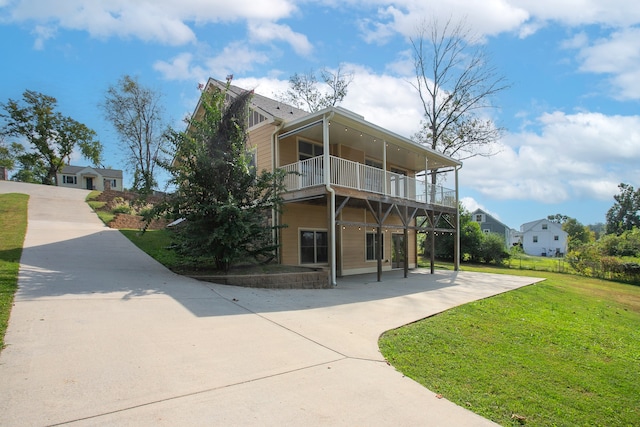 rear view of house featuring a balcony and a lawn