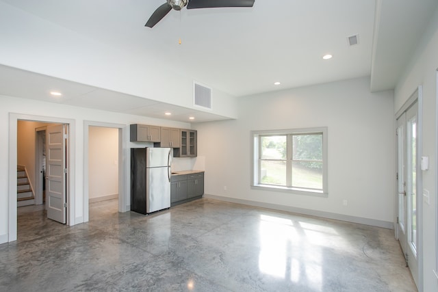 kitchen featuring ceiling fan, stainless steel fridge, and concrete floors