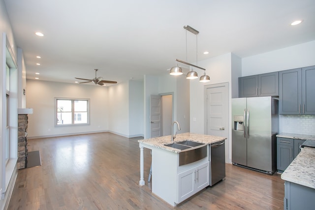 kitchen with ceiling fan, sink, decorative light fixtures, a kitchen island with sink, and stainless steel appliances