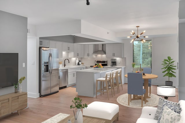 kitchen featuring appliances with stainless steel finishes, decorative backsplash, a kitchen island, light wood-type flooring, and wall chimney range hood