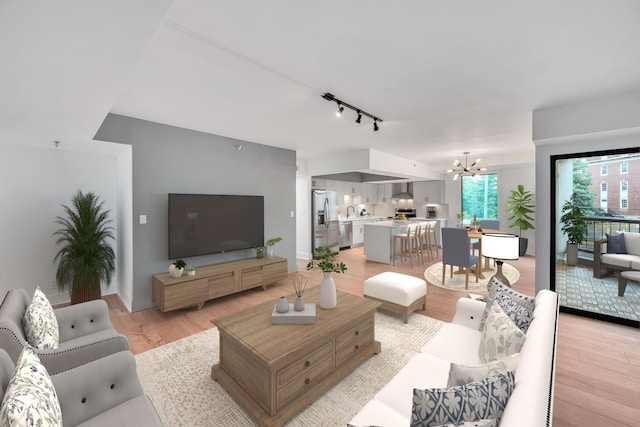 living room featuring track lighting, sink, light wood-type flooring, and a chandelier