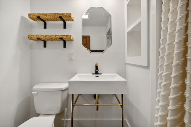 bathroom featuring sink, toilet, and curtained shower