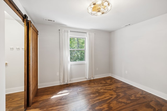 unfurnished bedroom with dark wood-type flooring and a barn door