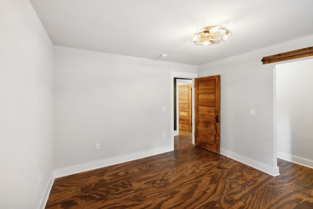 empty room with a barn door and dark hardwood / wood-style floors