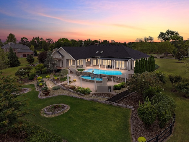 pool at dusk with a yard and a patio area