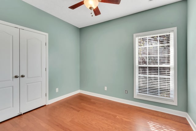 unfurnished bedroom featuring a closet, wood-type flooring, and ceiling fan