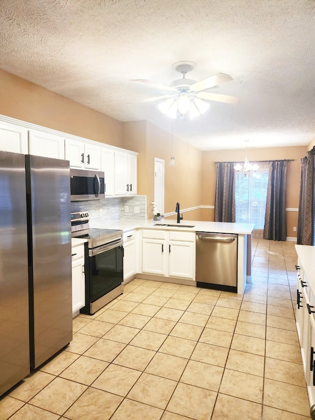 kitchen featuring pendant lighting, appliances with stainless steel finishes, sink, and white cabinetry