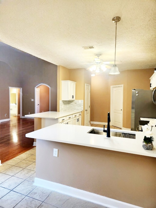 kitchen with ceiling fan, light tile patterned flooring, sink, kitchen peninsula, and decorative light fixtures