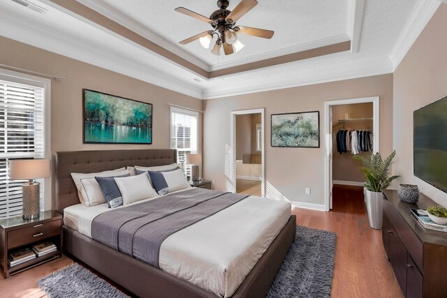 bedroom with a spacious closet, a closet, light wood-type flooring, ceiling fan, and ornamental molding