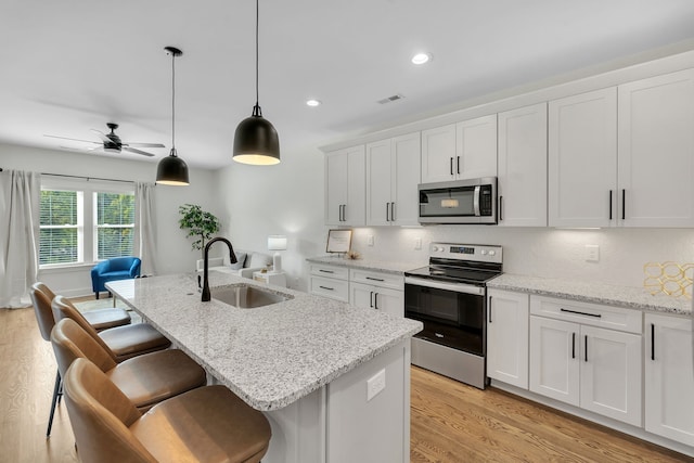 kitchen featuring a kitchen island with sink, white cabinetry, sink, and stainless steel appliances