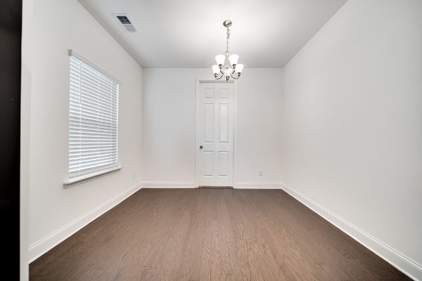 empty room featuring a chandelier and dark wood-type flooring