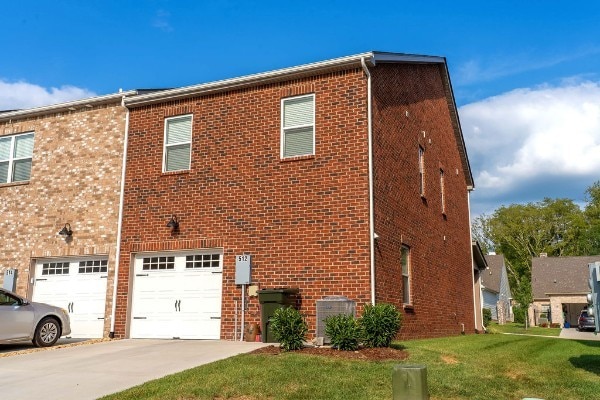 exterior space with a lawn, a garage, and central AC