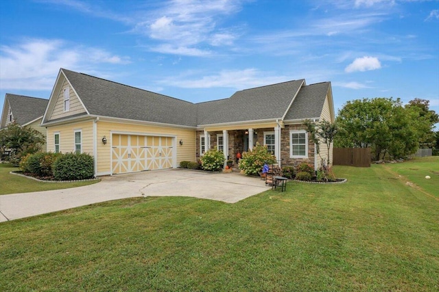 view of front of home featuring driveway, a front yard, stone siding, fence, and an attached garage
