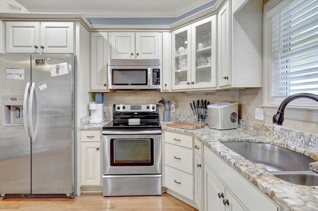 kitchen featuring light wood-type flooring, sink, white cabinets, appliances with stainless steel finishes, and crown molding