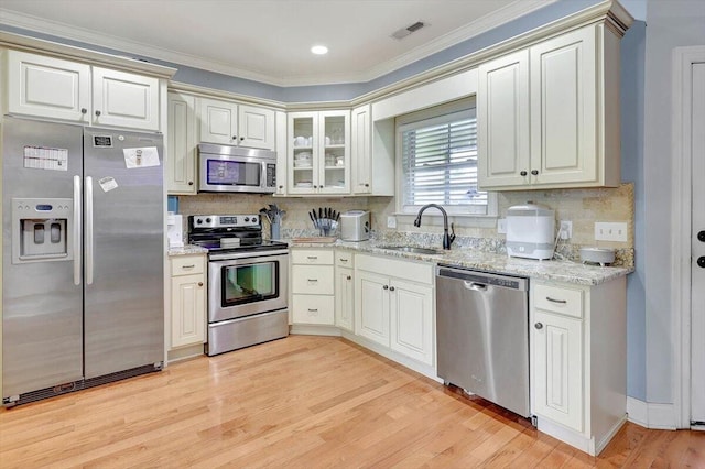 kitchen featuring appliances with stainless steel finishes, crown molding, light hardwood / wood-style floors, and sink