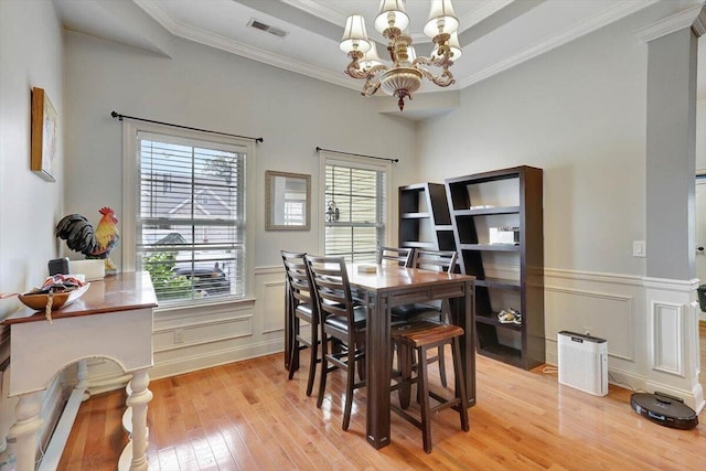 dining space featuring light hardwood / wood-style flooring, crown molding, a chandelier, and a tray ceiling