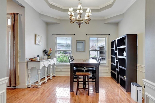 dining room featuring crown molding, a tray ceiling, an inviting chandelier, and light hardwood / wood-style flooring