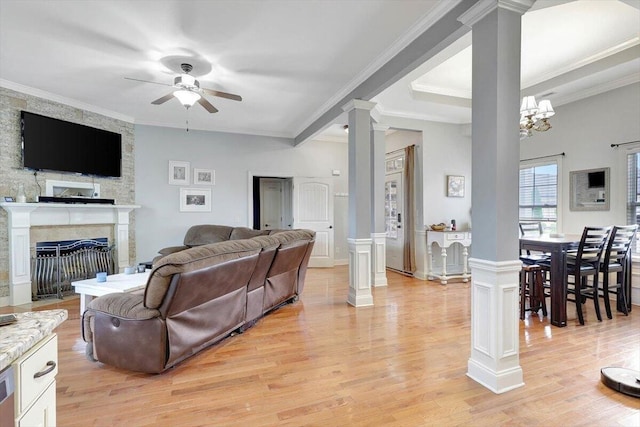 living room with light wood-type flooring, ceiling fan with notable chandelier, crown molding, and ornate columns