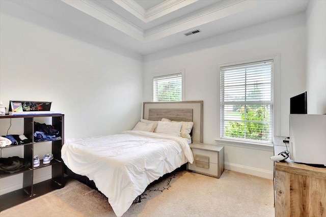 bedroom with ornamental molding, a tray ceiling, and carpet flooring