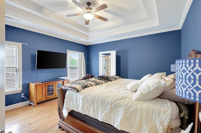 bedroom featuring ceiling fan, light hardwood / wood-style flooring, ornamental molding, and a tray ceiling