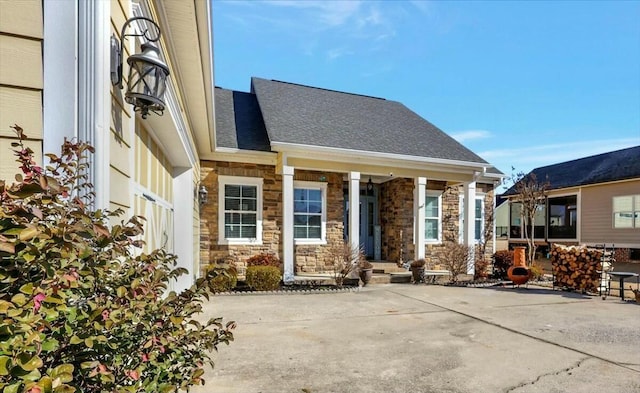 exterior space featuring stone siding and roof with shingles