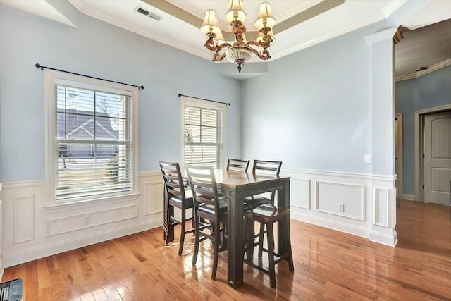 dining area featuring visible vents, a chandelier, crown molding, light wood finished floors, and a raised ceiling