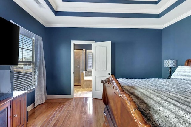 bedroom featuring hardwood / wood-style floors, a tray ceiling, baseboards, and crown molding