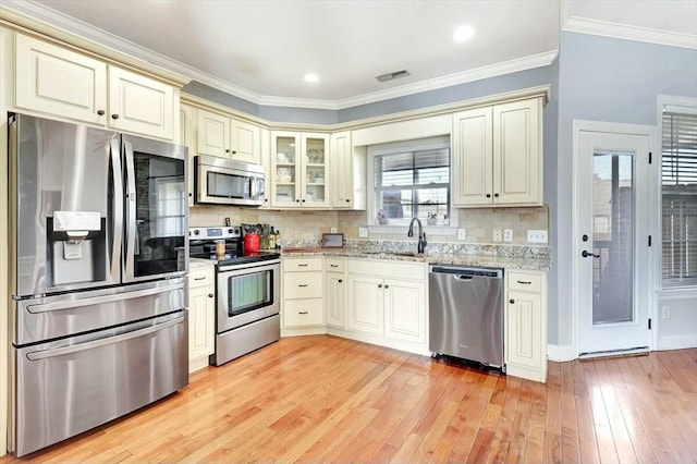 kitchen featuring ornamental molding, cream cabinetry, a sink, visible vents, and appliances with stainless steel finishes