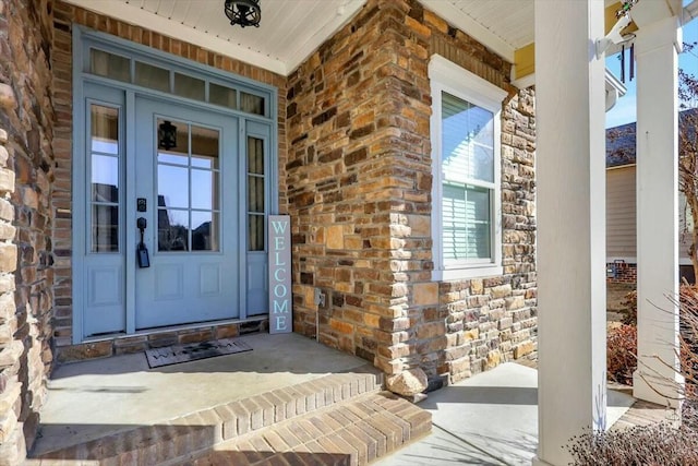 view of exterior entry with a porch, stone siding, and french doors