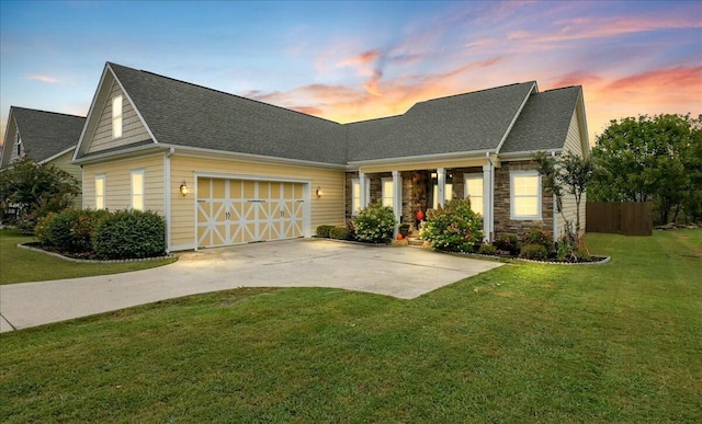 view of front facade with driveway, a front yard, stone siding, an attached garage, and a shingled roof