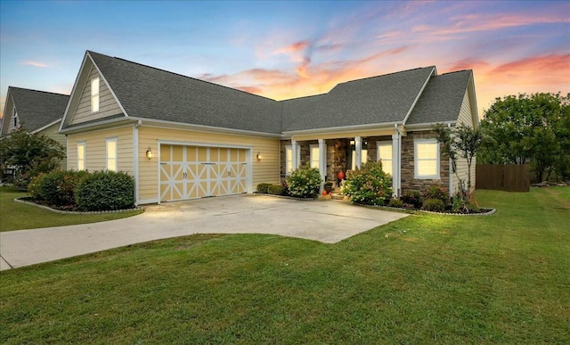 view of front facade featuring roof with shingles, concrete driveway, a front lawn, a garage, and stone siding