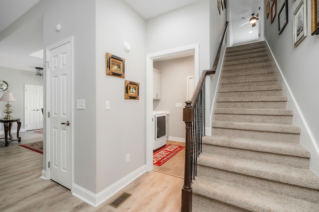 stairway featuring wood-type flooring, ceiling fan, and a high ceiling