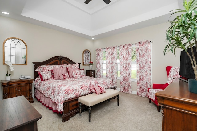 bedroom featuring ceiling fan, light colored carpet, and a tray ceiling