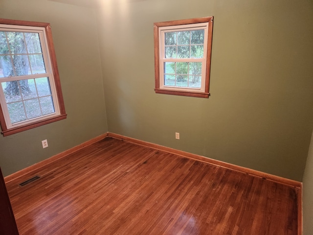 empty room with hardwood / wood-style floors and a healthy amount of sunlight