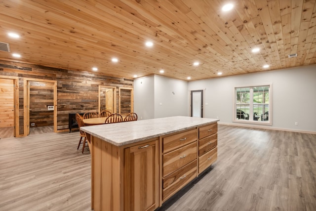 kitchen featuring light hardwood / wood-style flooring, wood walls, a center island, and wooden ceiling