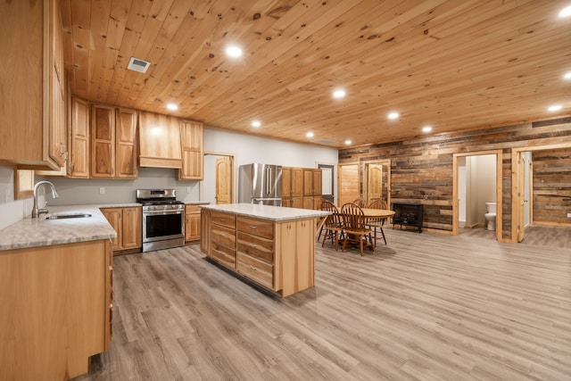 kitchen with appliances with stainless steel finishes, light hardwood / wood-style floors, wooden ceiling, a center island, and wooden walls