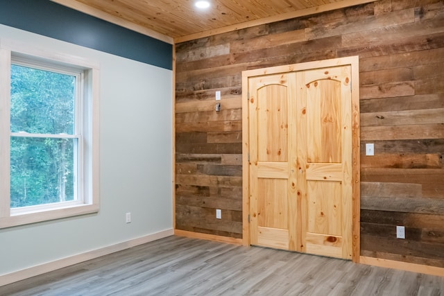 unfurnished bedroom featuring multiple windows, wood walls, and hardwood / wood-style floors