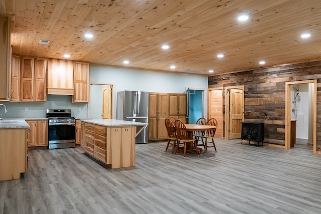 kitchen featuring sink, wood walls, a kitchen island, light hardwood / wood-style flooring, and stainless steel appliances