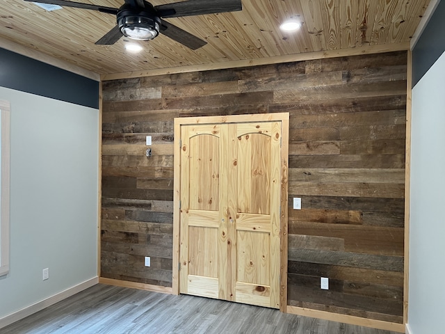 unfurnished bedroom featuring ceiling fan, wooden walls, hardwood / wood-style floors, and wooden ceiling