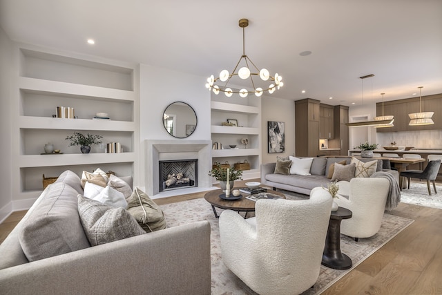 living room featuring built in shelves, wood-type flooring, and a notable chandelier