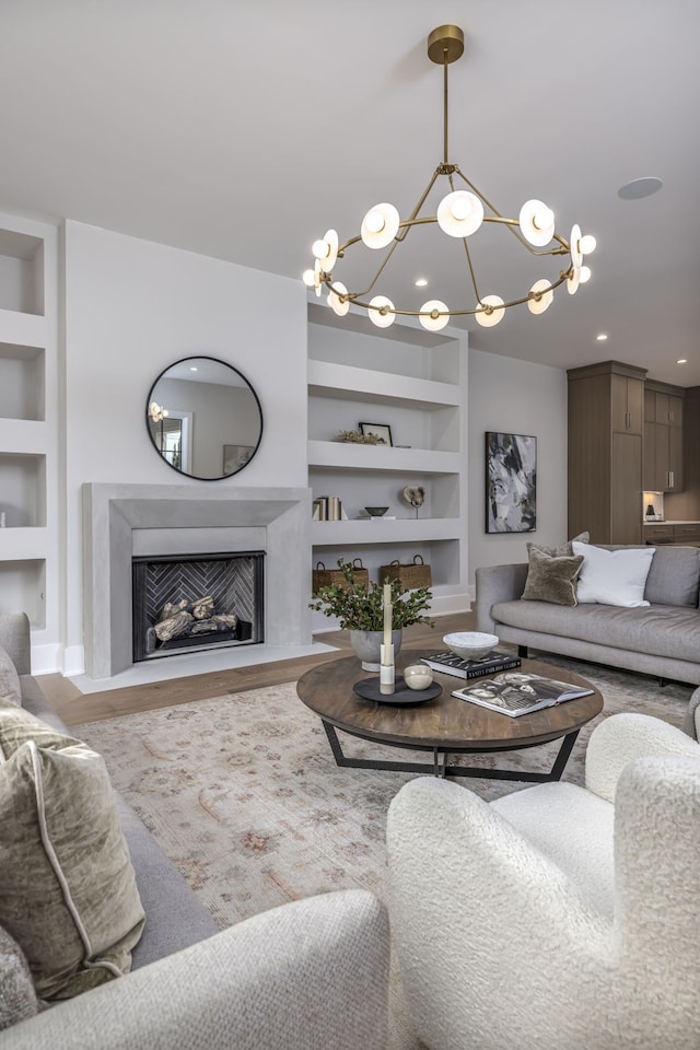 living room featuring built in features, wood-type flooring, and a notable chandelier