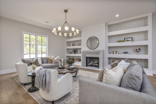 living room with built in shelves, light wood-type flooring, and a notable chandelier