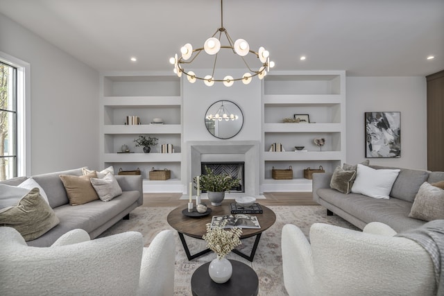 living room featuring built in features, light hardwood / wood-style flooring, and an inviting chandelier