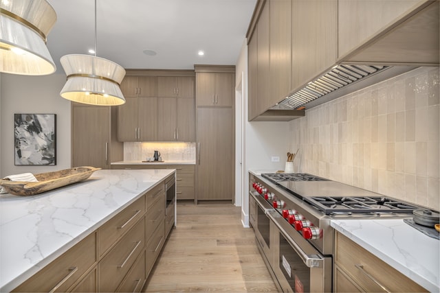 kitchen featuring light stone countertops, light wood-type flooring, tasteful backsplash, range with two ovens, and hanging light fixtures